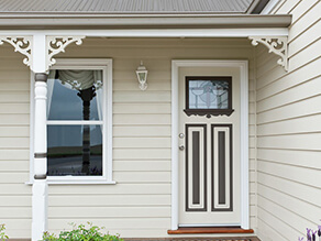 Cream Weatherboard with Fretwork and White Fascia and Dark Brown Detailing on Door with Tiled Porch
